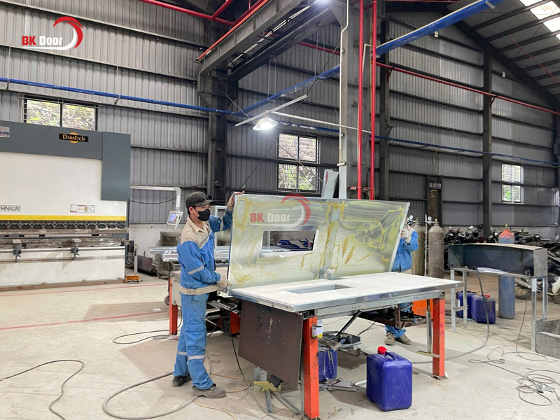 Công nhân tại nhà máy BK DOOR đang bôi keo và ghép cánh cửa thép chóng cháy giúp liên kết lõi và vỏ